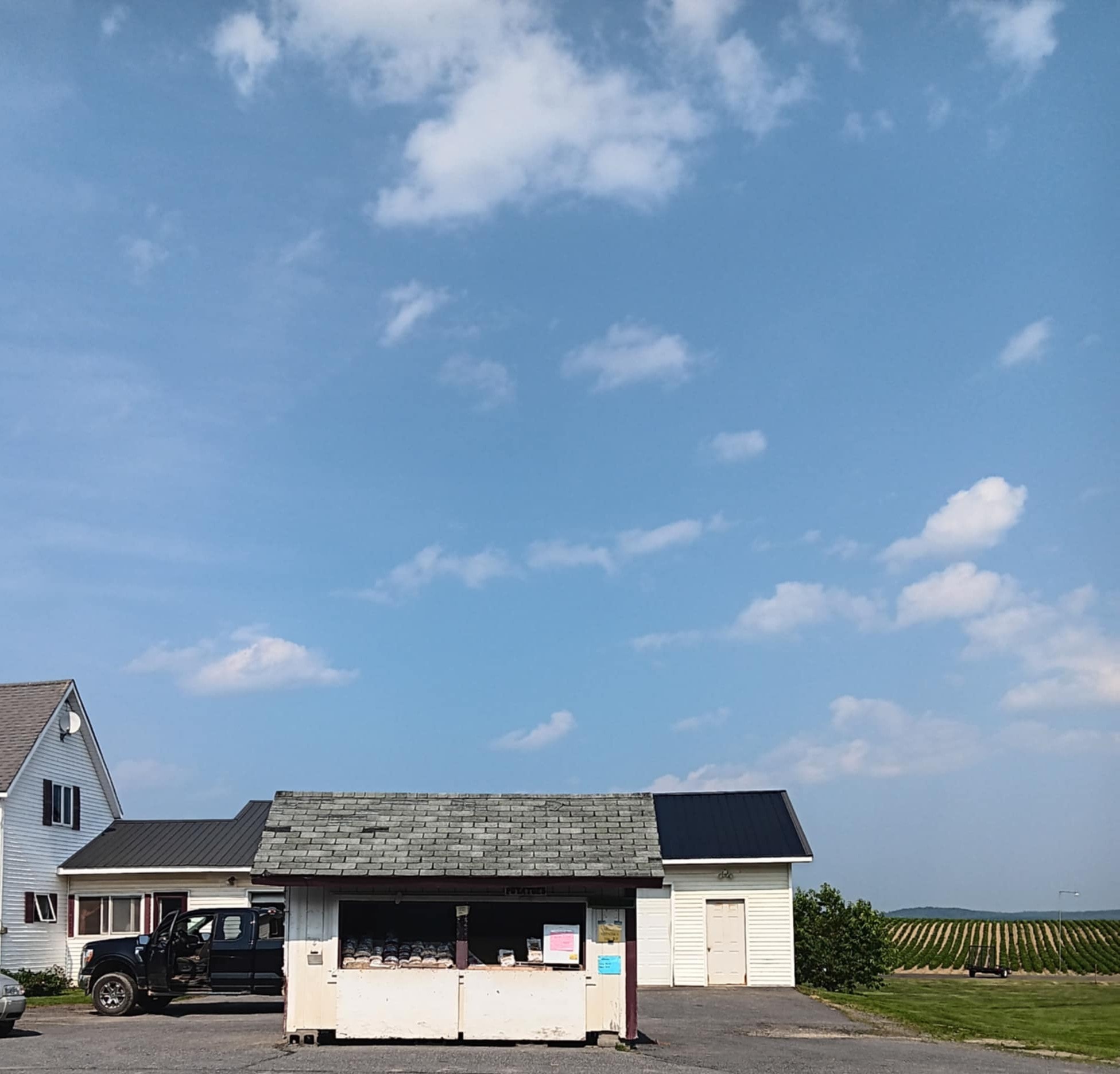 Bradstreet Farm stand on Main Street in Bridgewater, Maine with potato bags and farm fields behind
