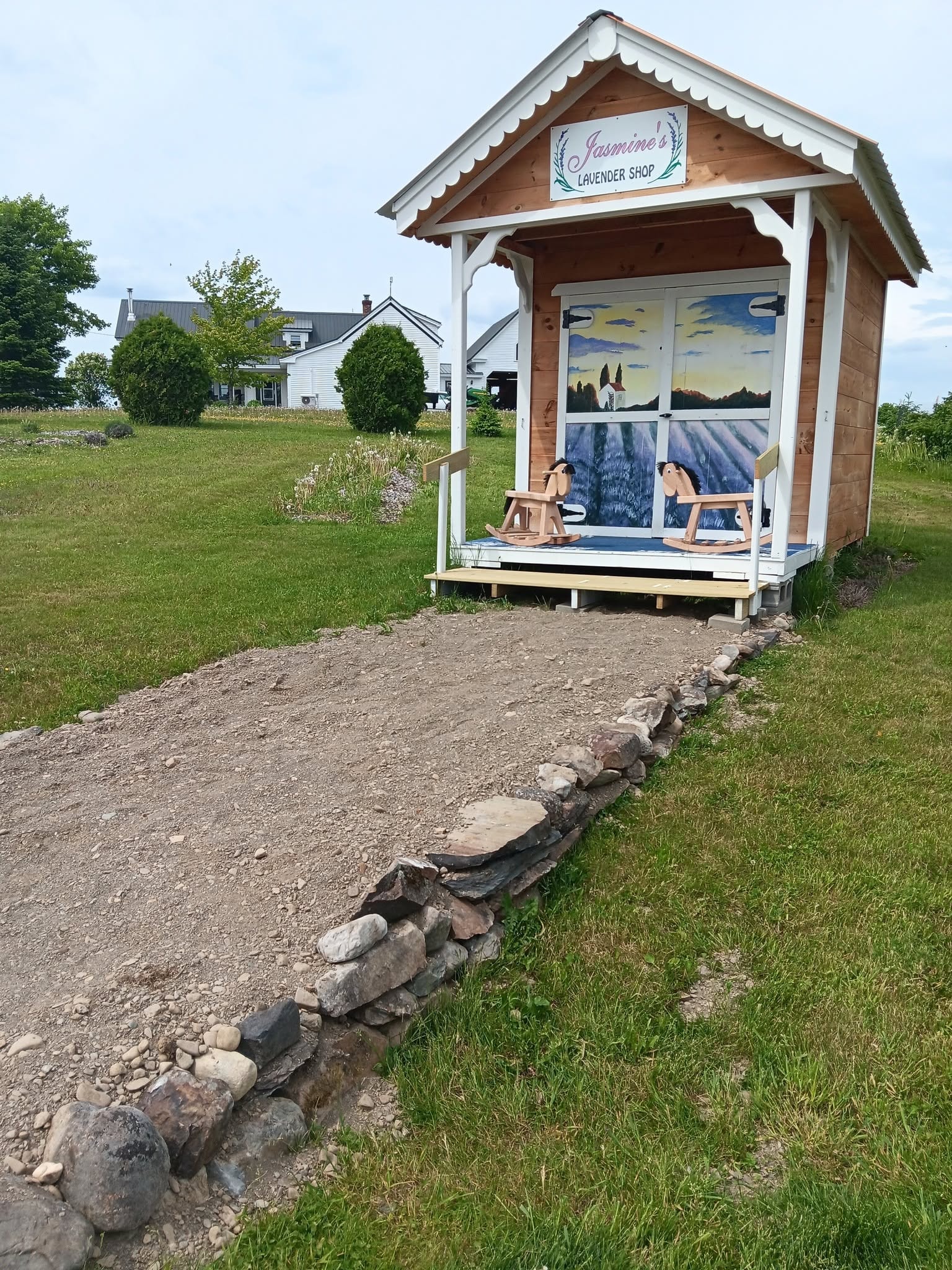 Jasmine's Lavender Shop — charming cedar kiosk with hand-painted lavender mural doors and rocking horses on the porch, Dyer Brook, Maine