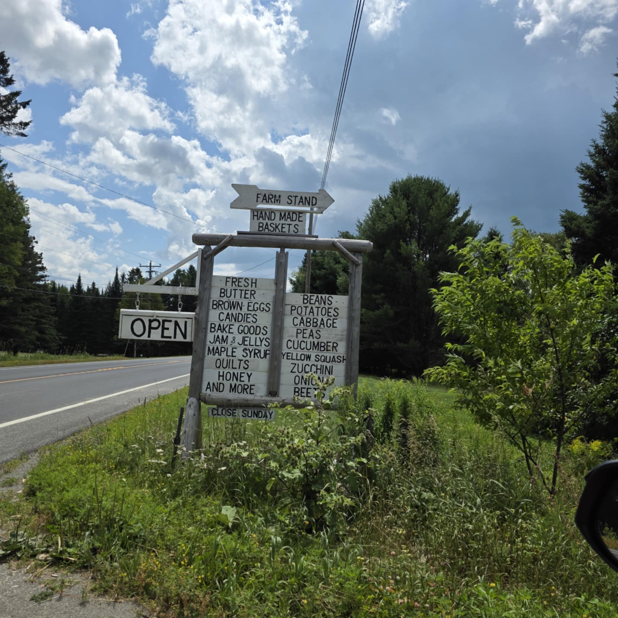 Organic Road Farm Stand roadside sign listing handmade baskets, produce, honey, preserves, and baked goods